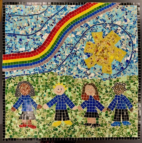 Mosaic children hold hands outdoors.