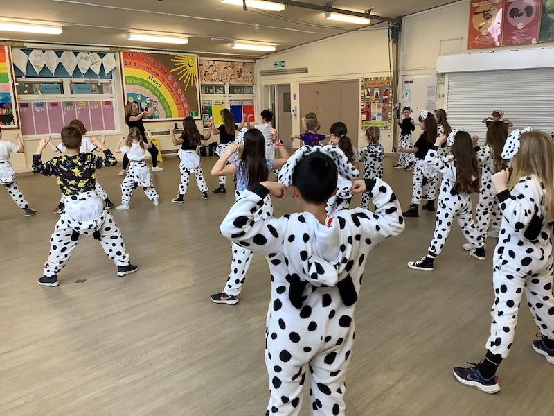 Children dancing, wearing dalmatian costumes, classroom.